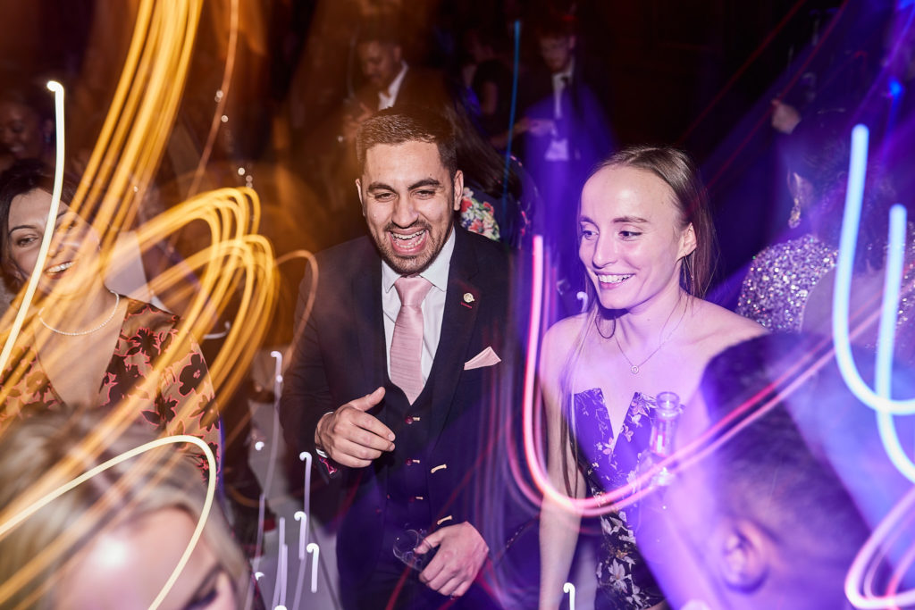 Wedding guests dancing among swirls of coloured light