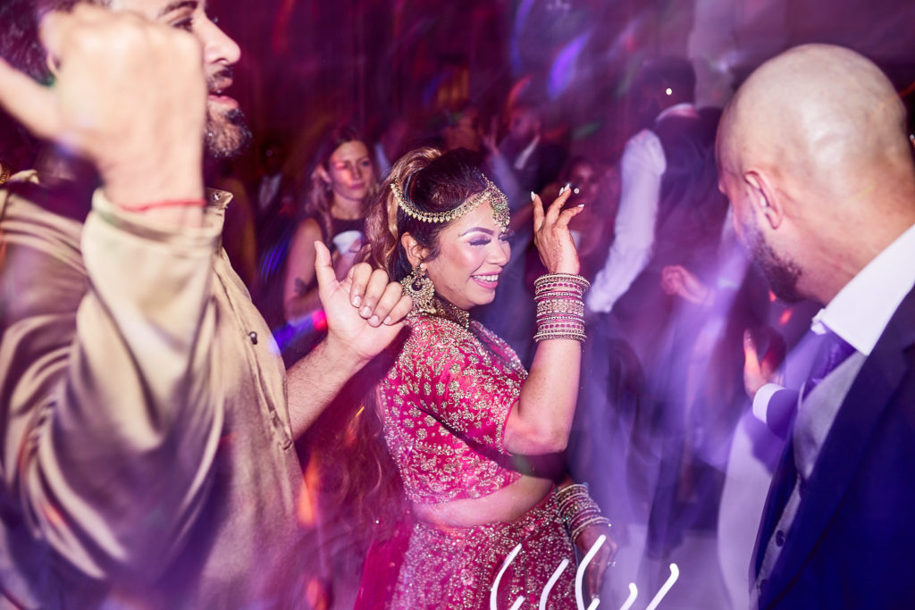 Bride in a red lehenga dancing among her guests