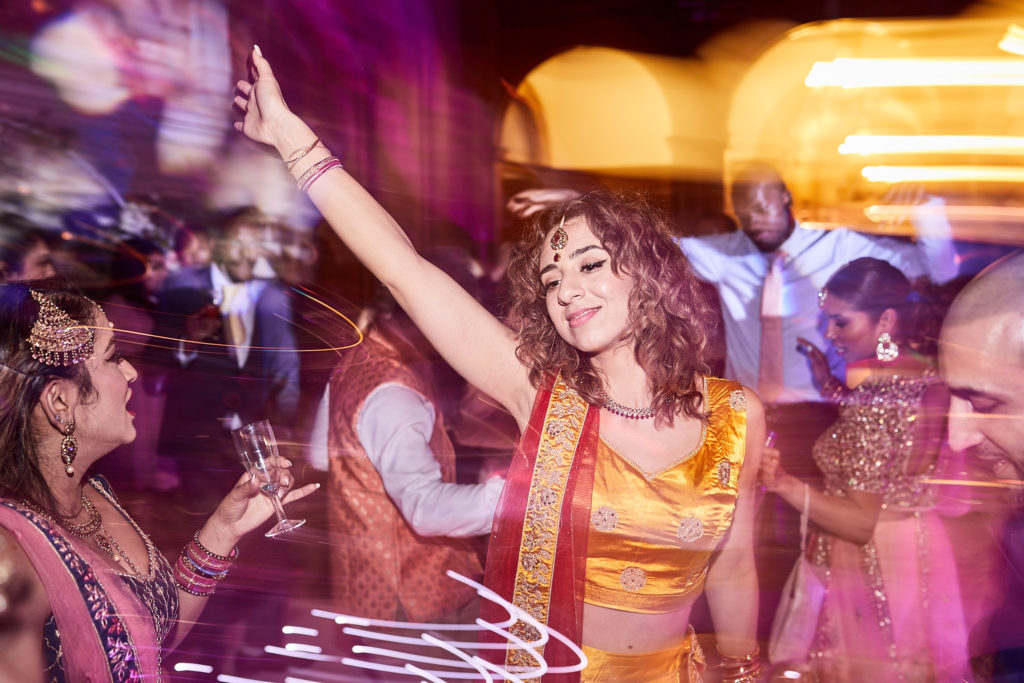 Bridesmaid in a yellow lehenga dancing with her arm in the air