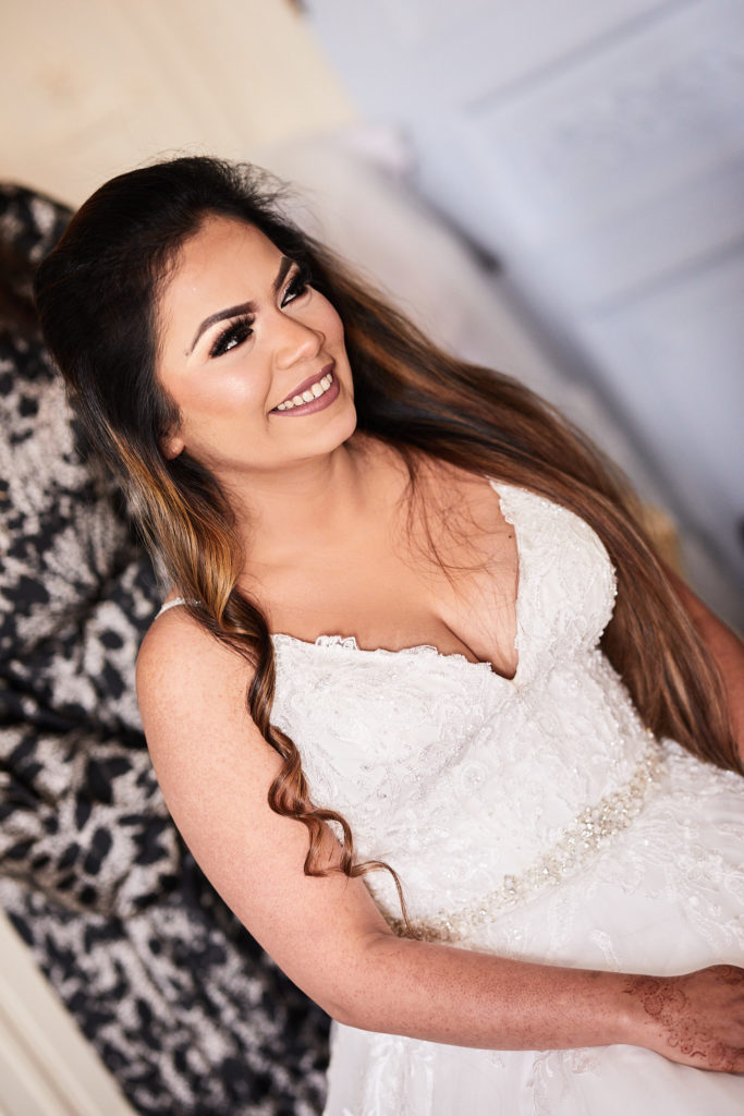 Bride smiling in her lace wedding dress with her hair in loose curls