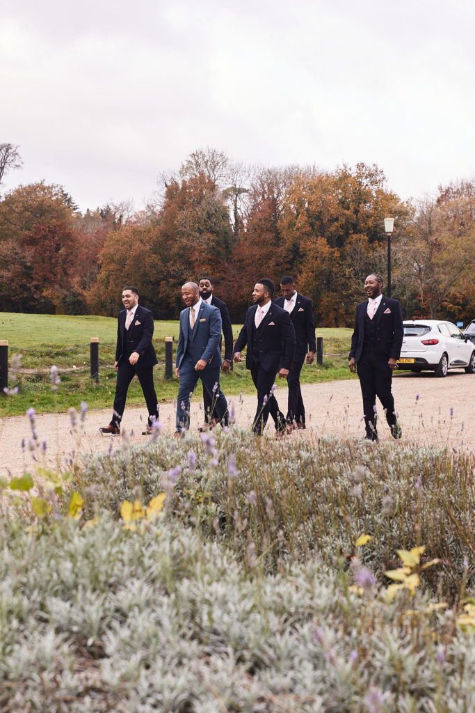 Groom and groomsmen walking up the drive at Addington Palace in autumn