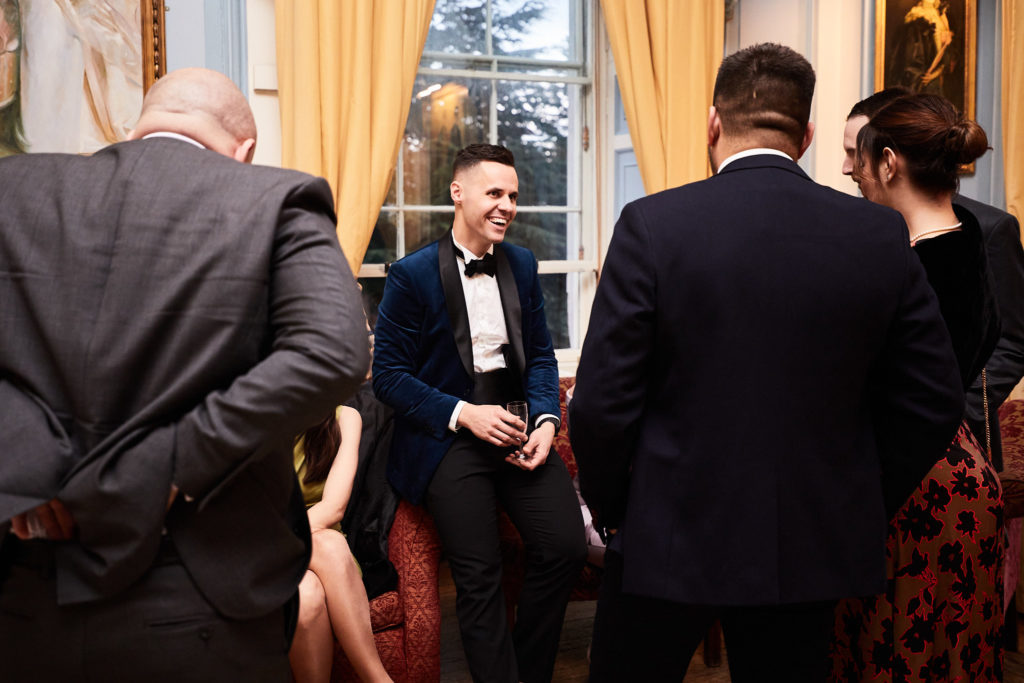 Wedding guest in a bow tie chatting with others at the drinks reception