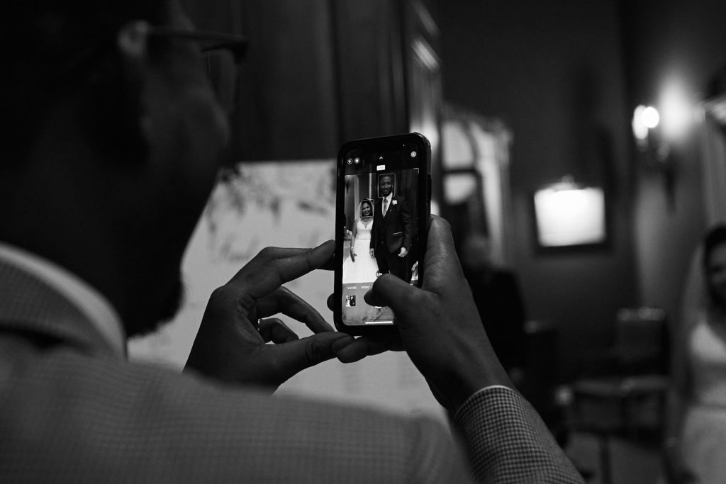 Black and white photo of a guest taking a picture on a phone