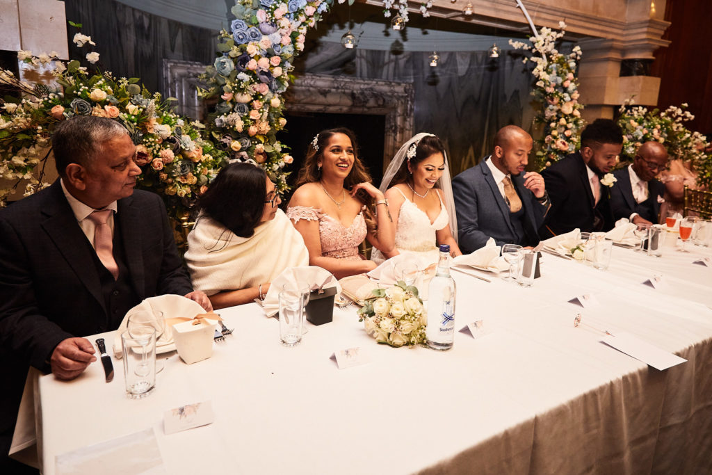 Bride and family seated at the top table beneath an arch of flowers