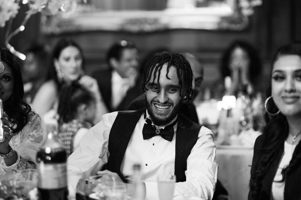 Black and white photo of a guest in a bow tie laughing during the speeches