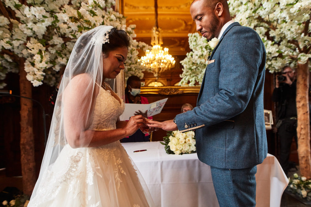 Bride placing the wedding ring on the groom's finger