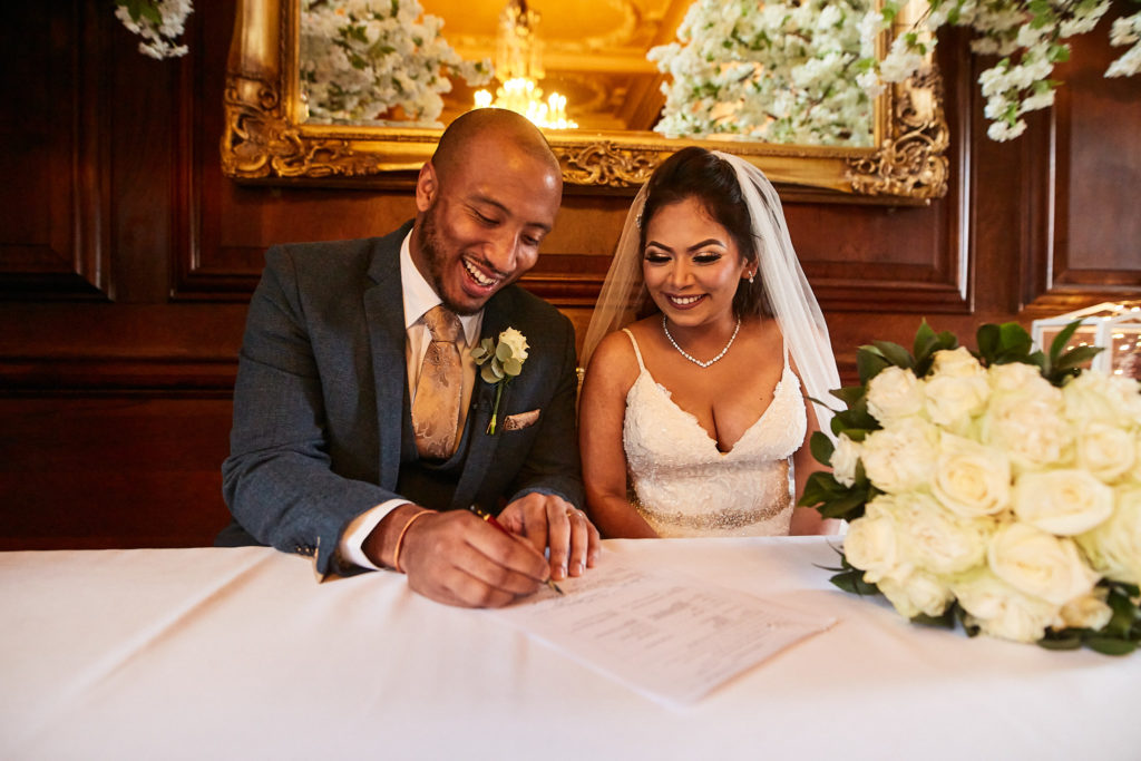 Bride and groom laughing as they sign the register