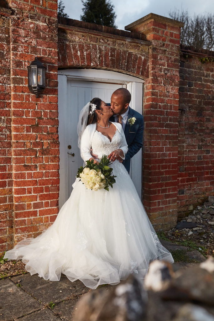Groom kissing the bride in a red-brick doorway at Addington Palace, Surrey