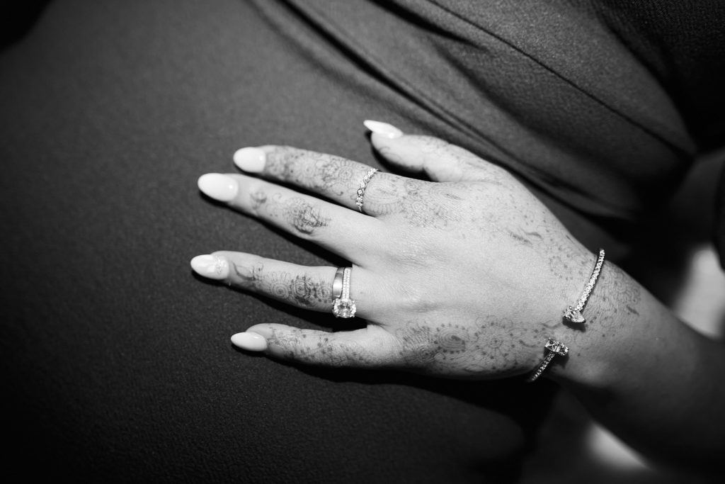 Close-up of a hand with an engagement ring resting on a dark dress