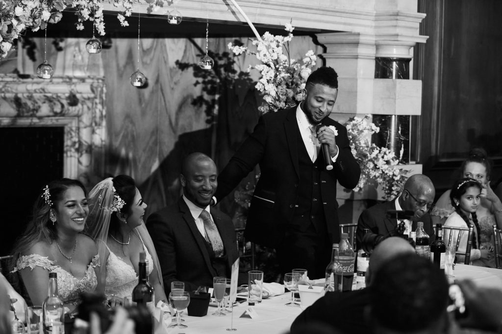 Black and white photo of a speech being given as the top table listens