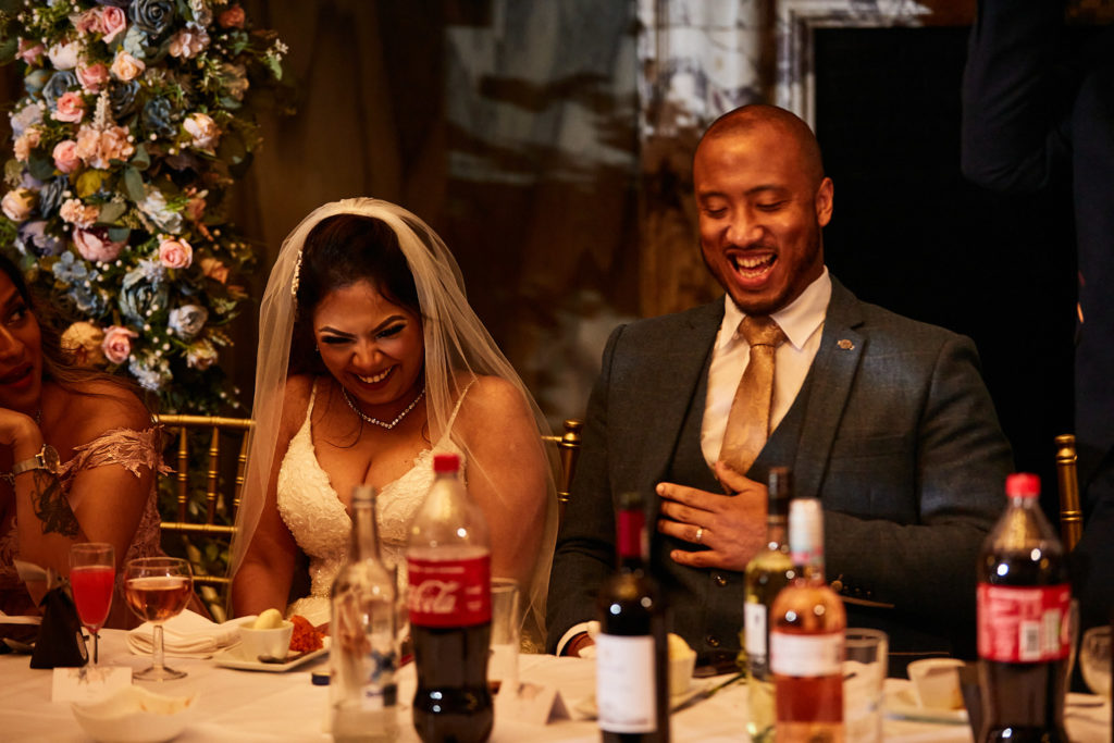 Bride and groom laughing at the top table during the speeches