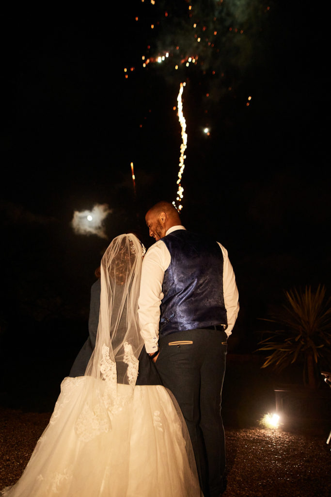 Bride and groom watching fireworks at night outside Addington Palace