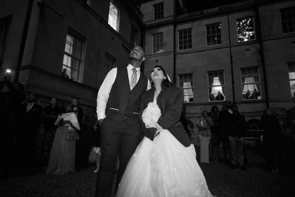 Black and white photo of the bride and groom outside Addington Palace at night