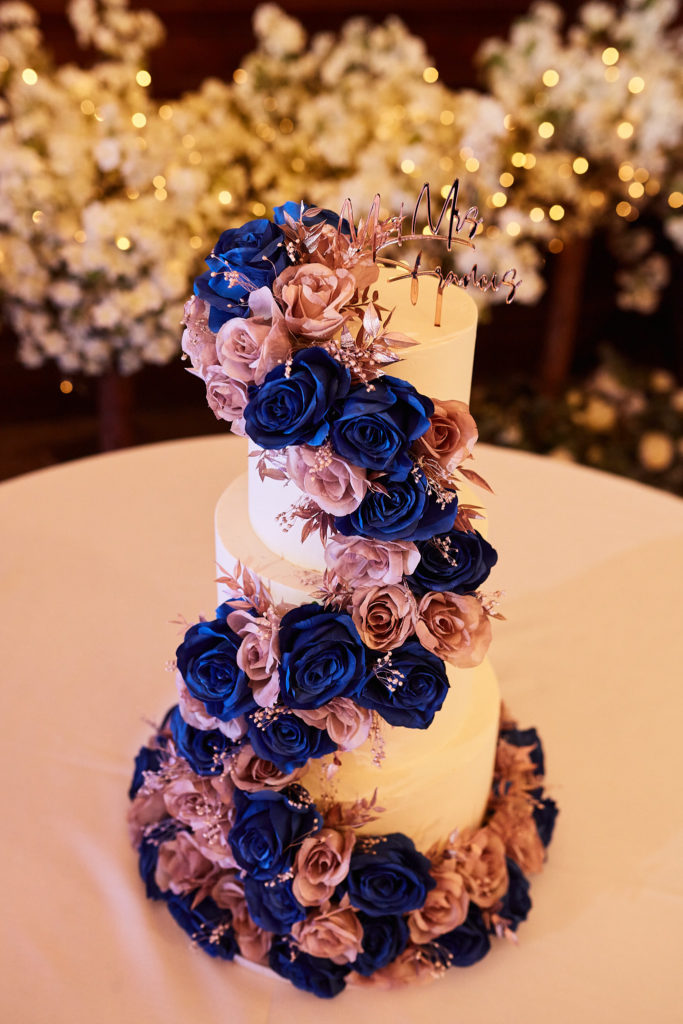 Tall wedding cake wrapped in a spiral of blue and pink roses