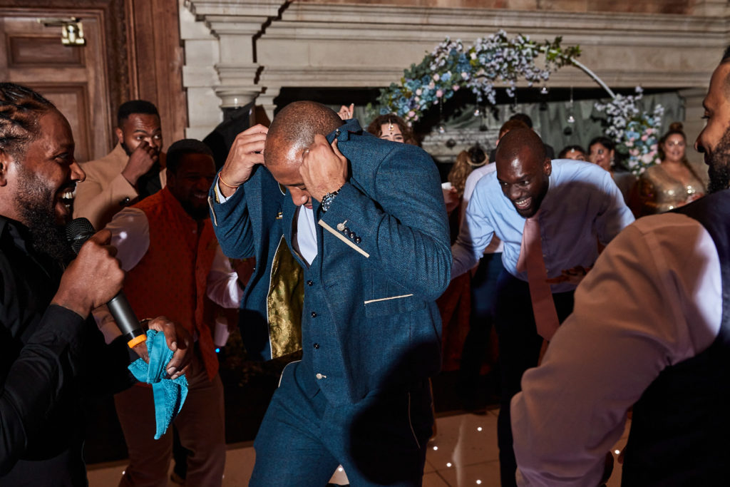 Groom dancing low to the floor as guests cheer him on