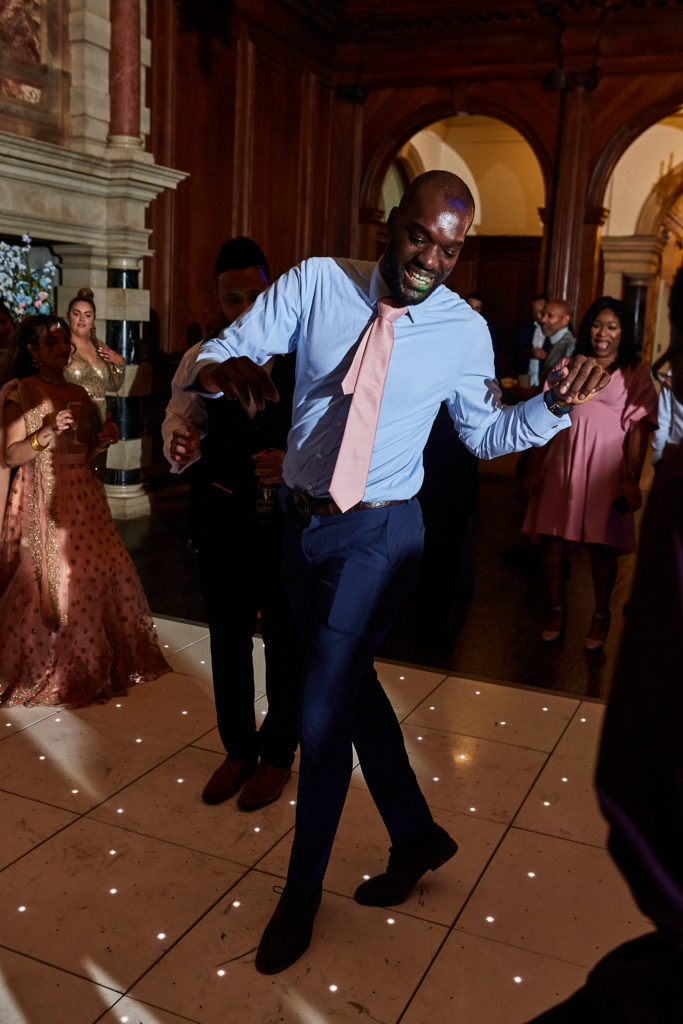 Guest in a blue shirt and pink tie dancing on the light-up dance floor