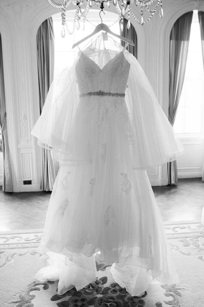 Black and white photo of the lace wedding dress hanging from a chandelier