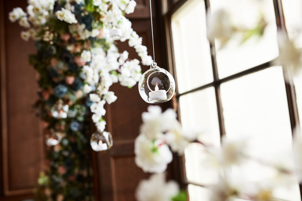 Garland of white flowers with a hanging glass bauble beside a window