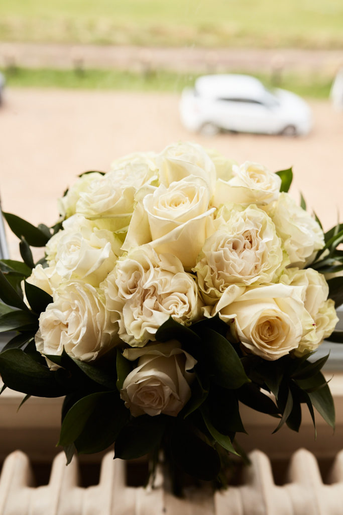 Bouquet of cream roses on a windowsill above the drive