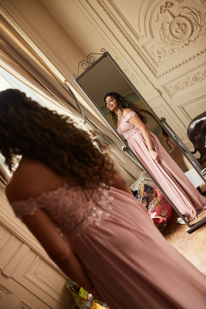 Bridesmaid in a blush pink dress reflected in a tall mirror
