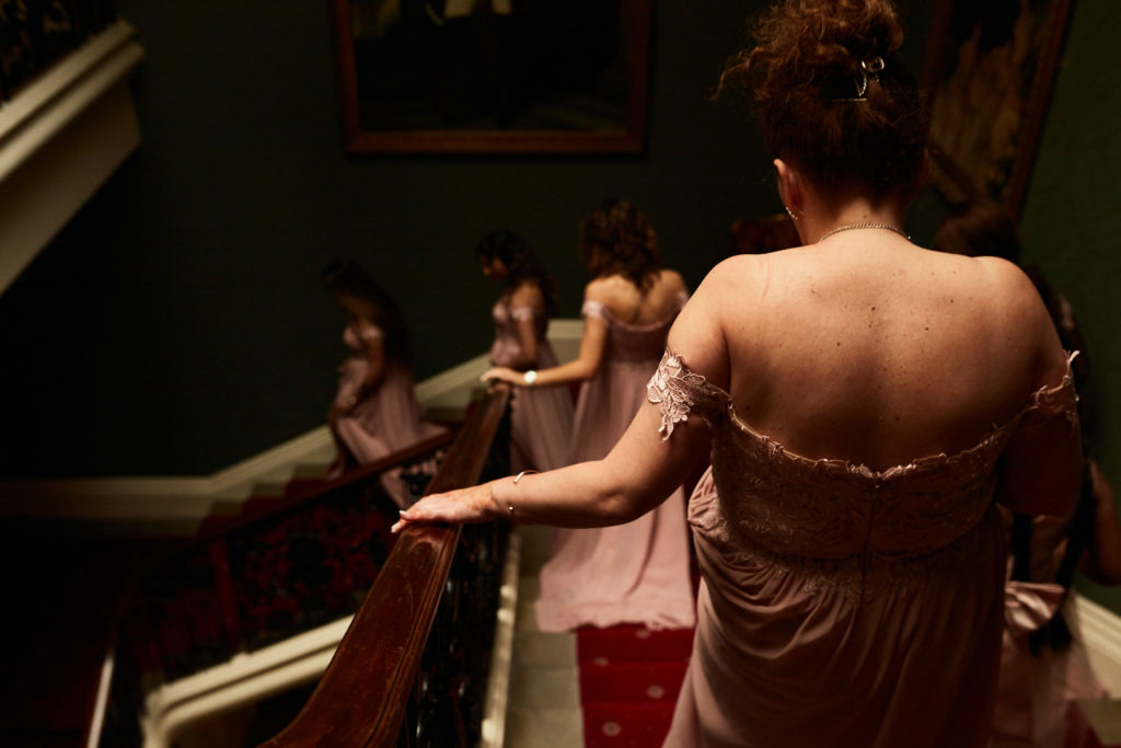 Bridesmaids coming down a dark staircase, seen from behind