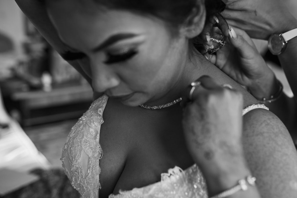 Black and white close-up of the bride's necklace being fastened