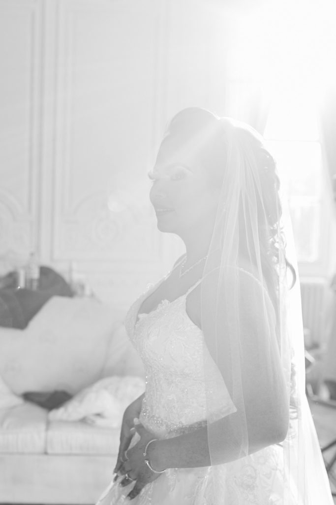 Black and white profile of the bride in her veil against a bright window