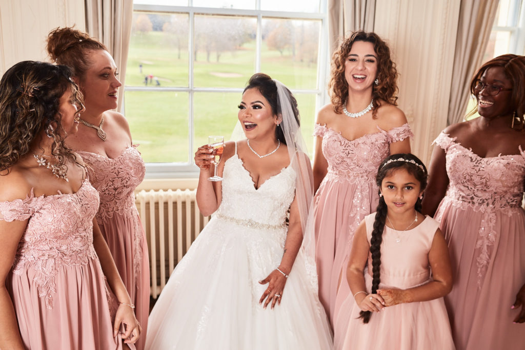 Bride laughing with her bridesmaids and flower girl before the ceremony