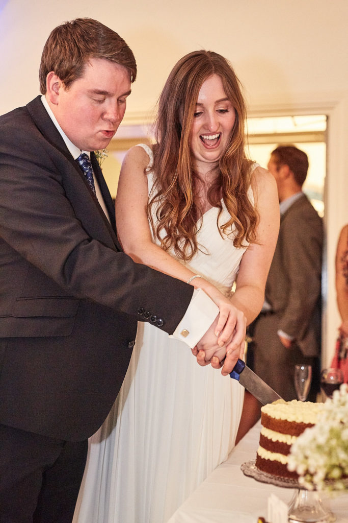 Bride and groom laughing as they cut their naked wedding cake