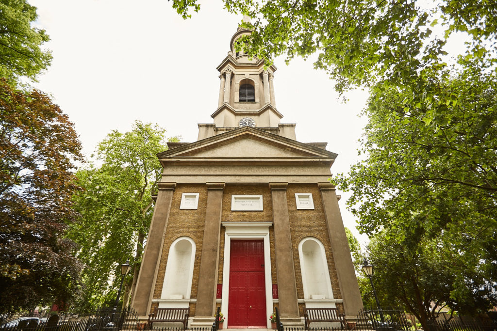 Brick church with a red door and white tower in central London