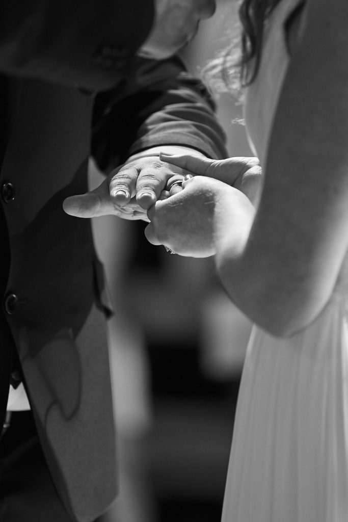 Black and white close-up of the bride and groom exchanging rings