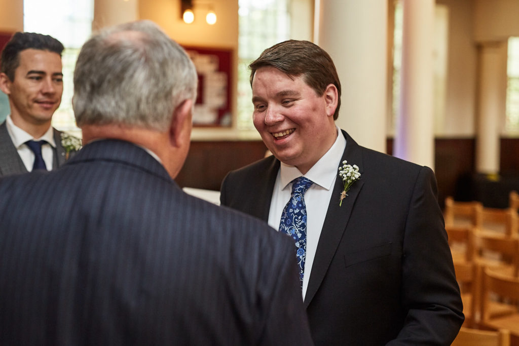 Groom laughing with guests inside the church