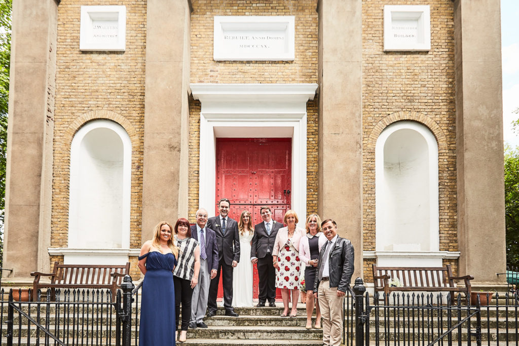 Wedding party on the church steps in front of the red door