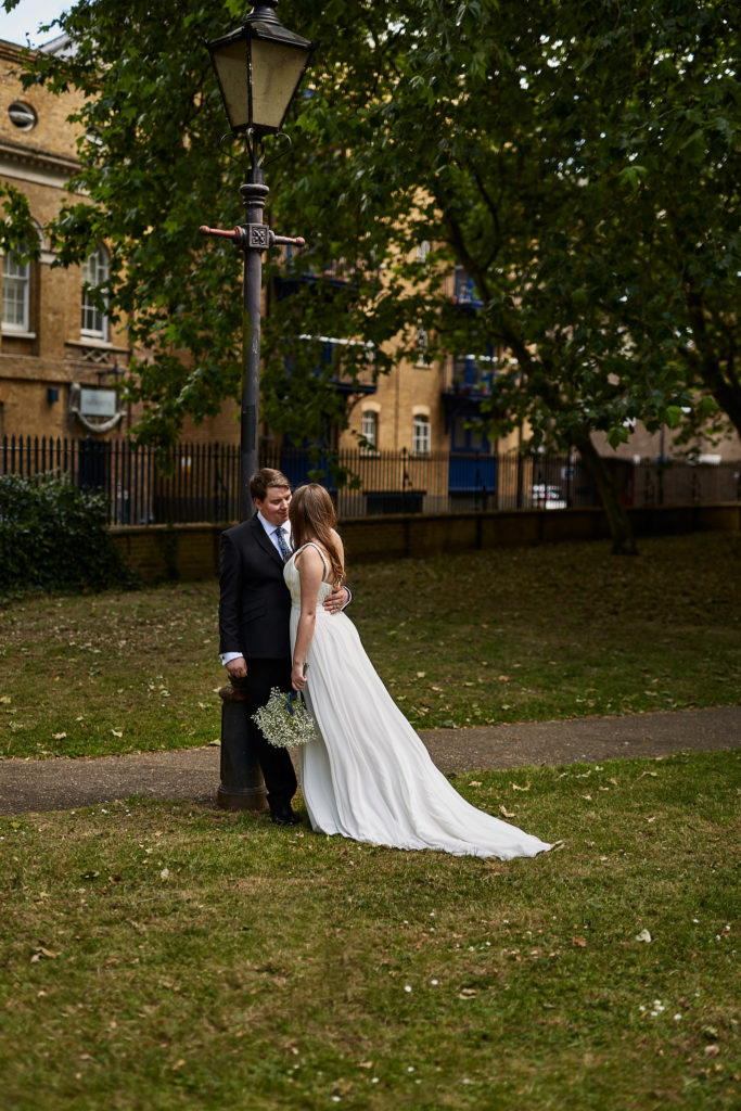 Bride and groom embracing under a lamp post in a London square