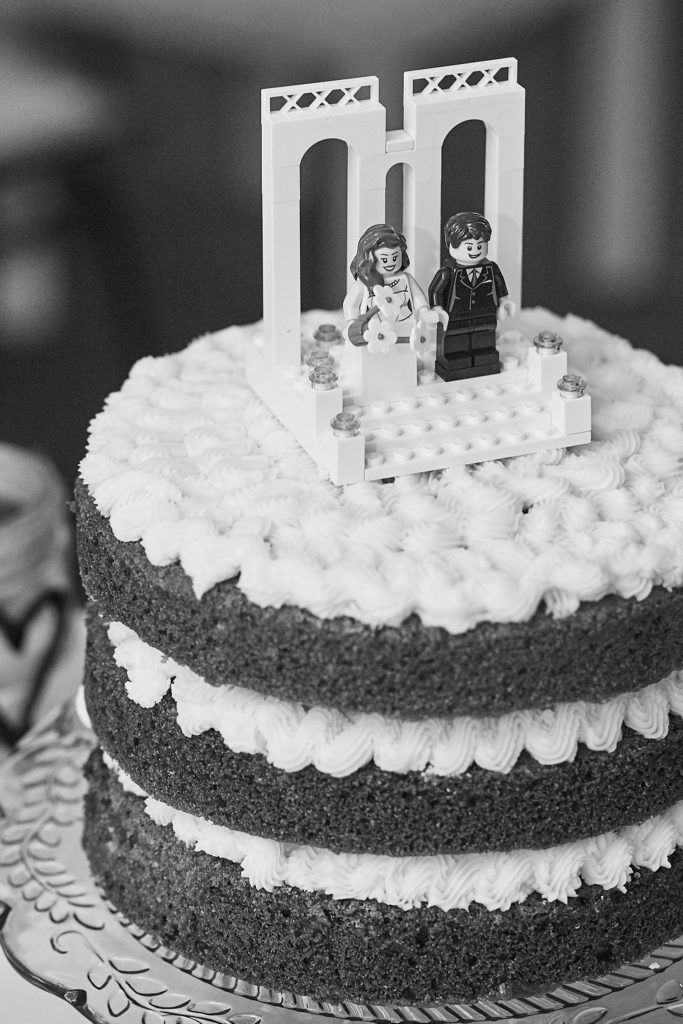 Black and white photo of the wedding cake topped with Lego bride and groom figures