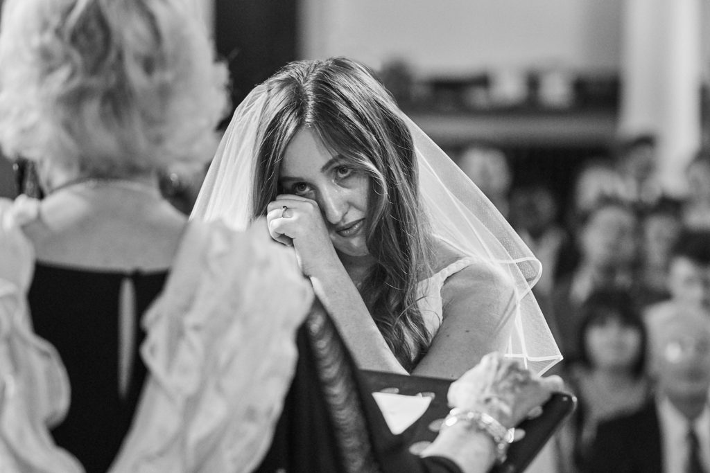 Black and white photo of the bride laughing behind her veil