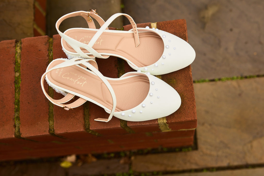 White strappy bridal shoes on a red brick step