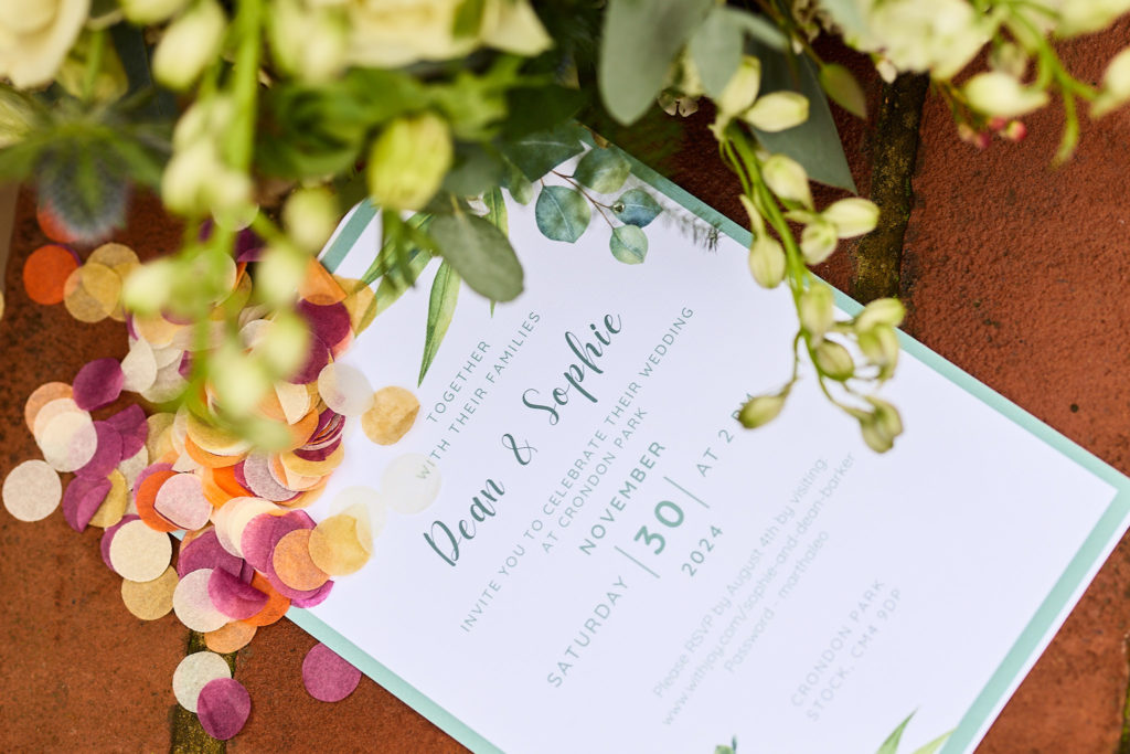 Wedding invitation surrounded by confetti petals and foliage
