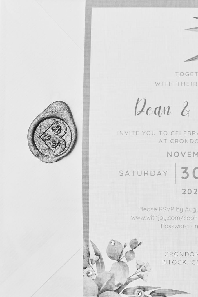 Black and white close-up of a wedding invitation with a wax seal