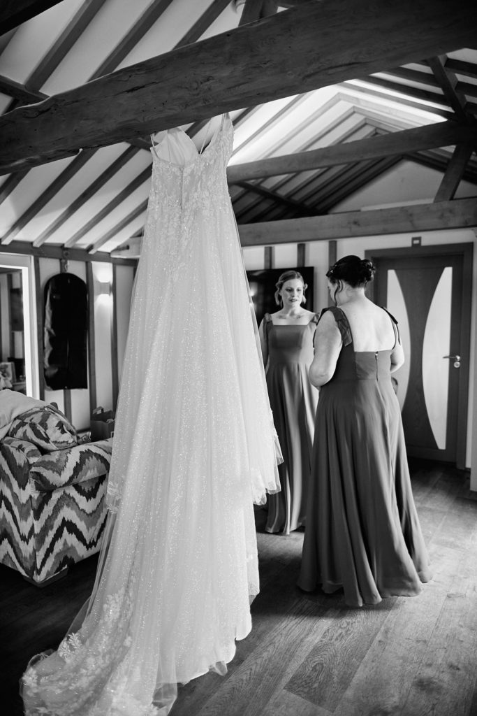 Bridesmaids chatting behind the hanging wedding dress, in black and white