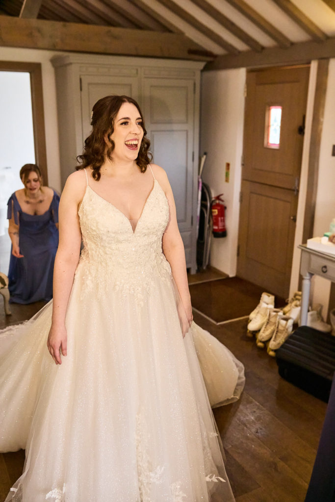 Bride laughing in her wedding dress in an oak-beamed bridal suite