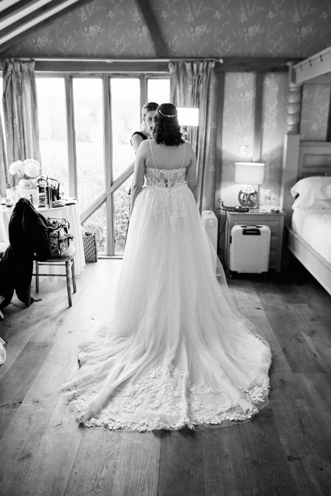 Black and white photo of the bride from behind, showing the long train of her wedding dress