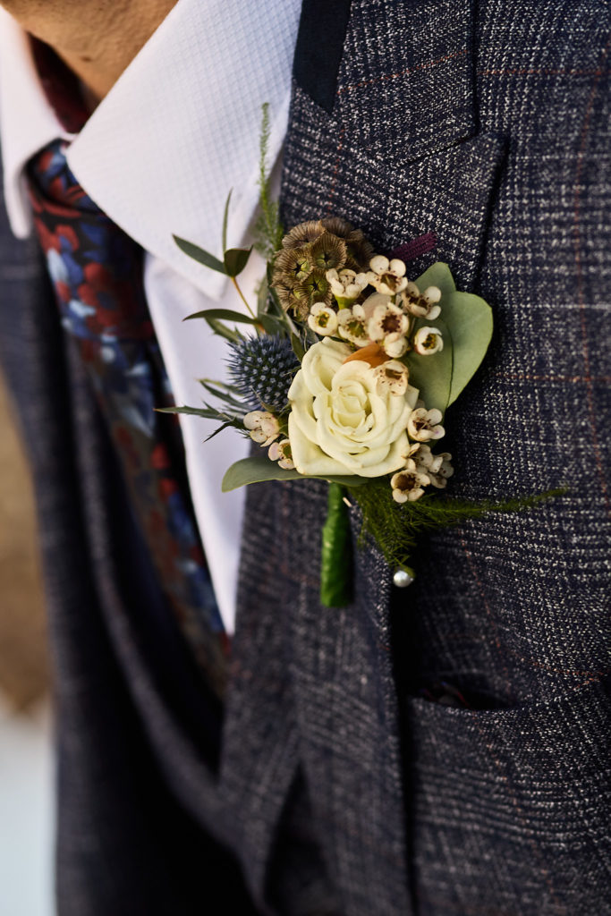 Close-up of the groom's buttonhole on a blue check suit