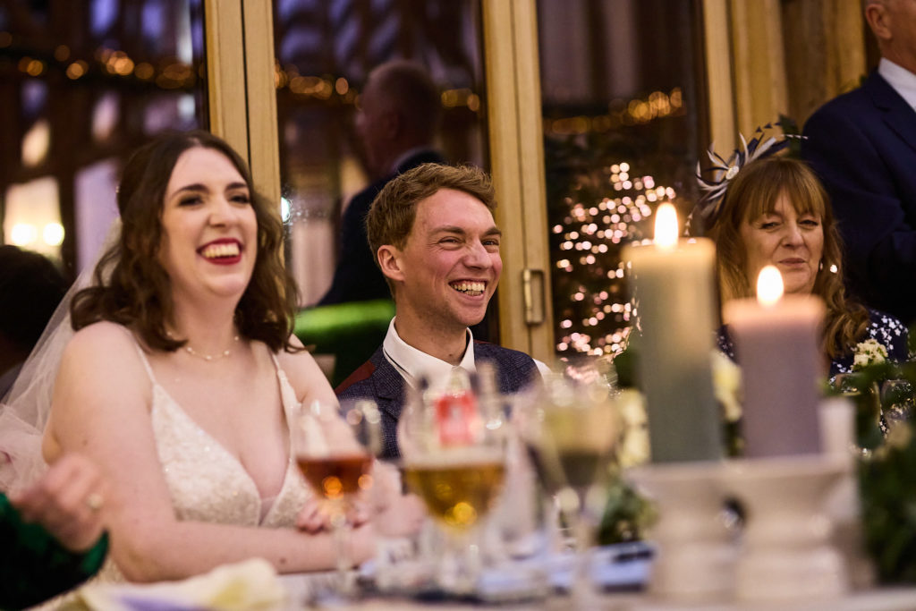 Bride laughing beside the groom at a candlelit reception table