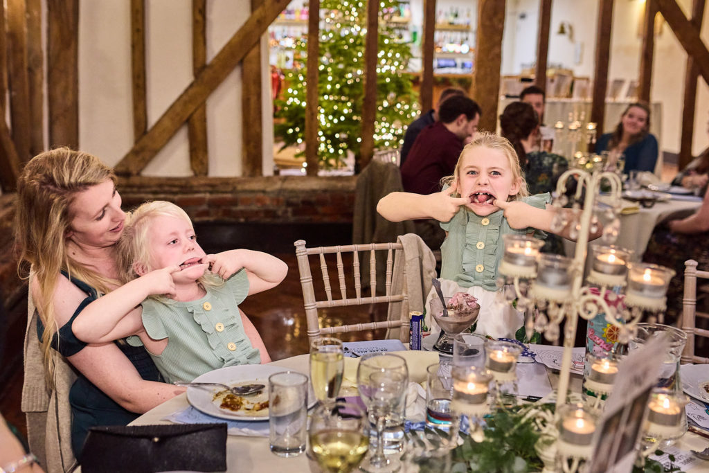 Young wedding guest pulling a funny face at a reception table in the barn