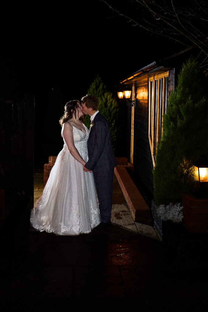 Bride and groom kissing outside the barn at Crondon Park at night