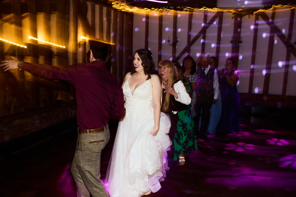 Bride dancing with guests on a purple-lit dance floor