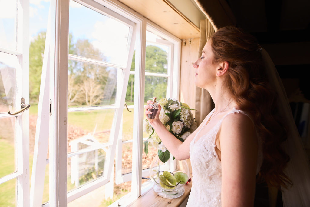 Bride holding her bouquet beside an open window