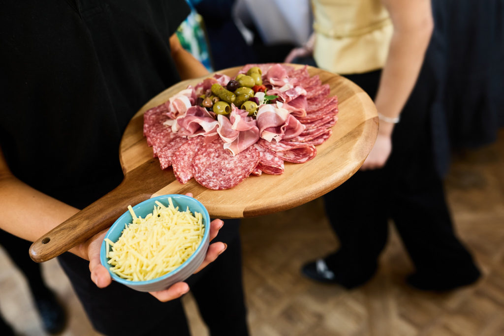 Sharing board of cured meats being carried to the tables