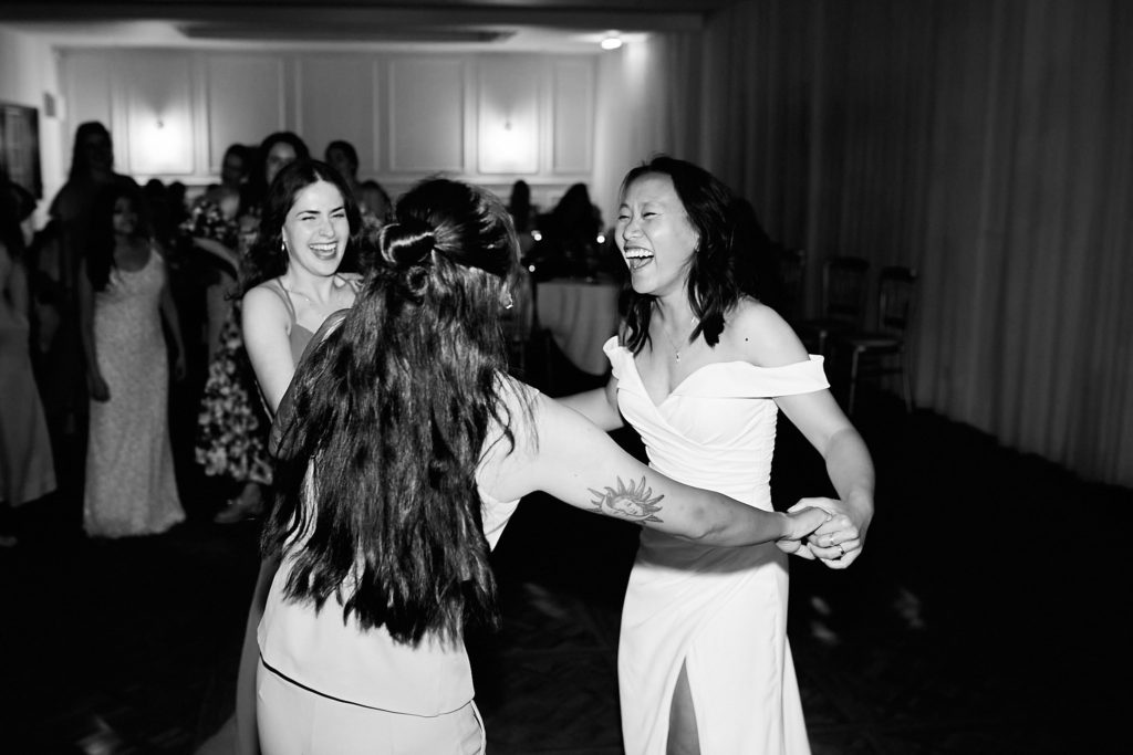 Black and white photo of a bride dancing with guests